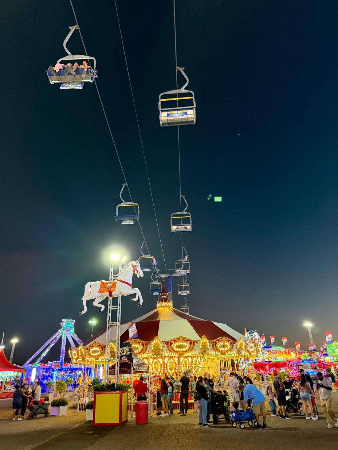 The Arizona State Fair at night, the carousel and sky ride lit up against a dark sky