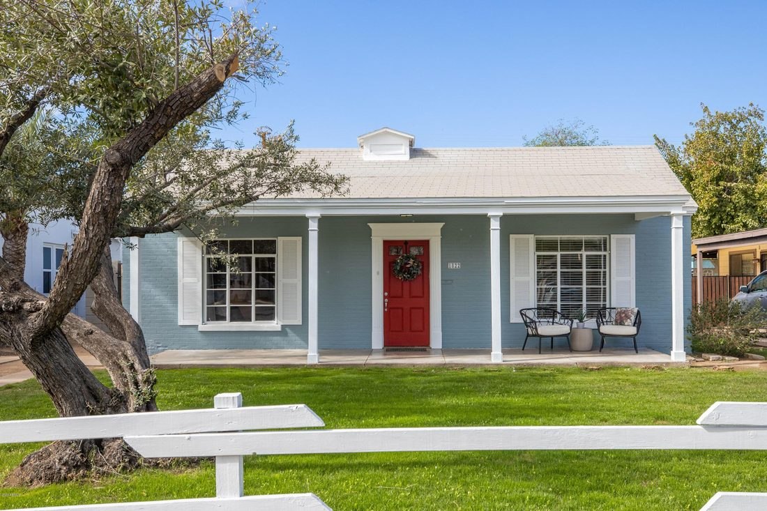 A restored historic bungalow in Fairview Place with a columned front porch and red door